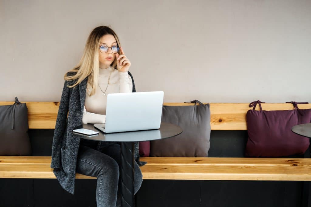 Woman on her phone and working on laptop in coffee shop